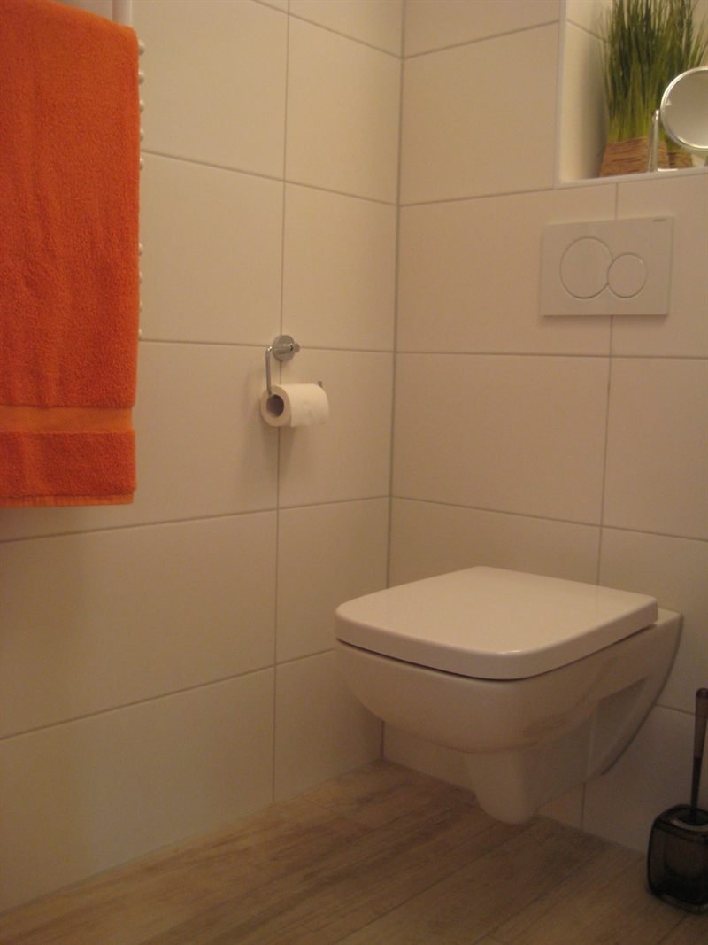 Wandhängendes WC im zweiten Badezimmer mit hellen Fliesen