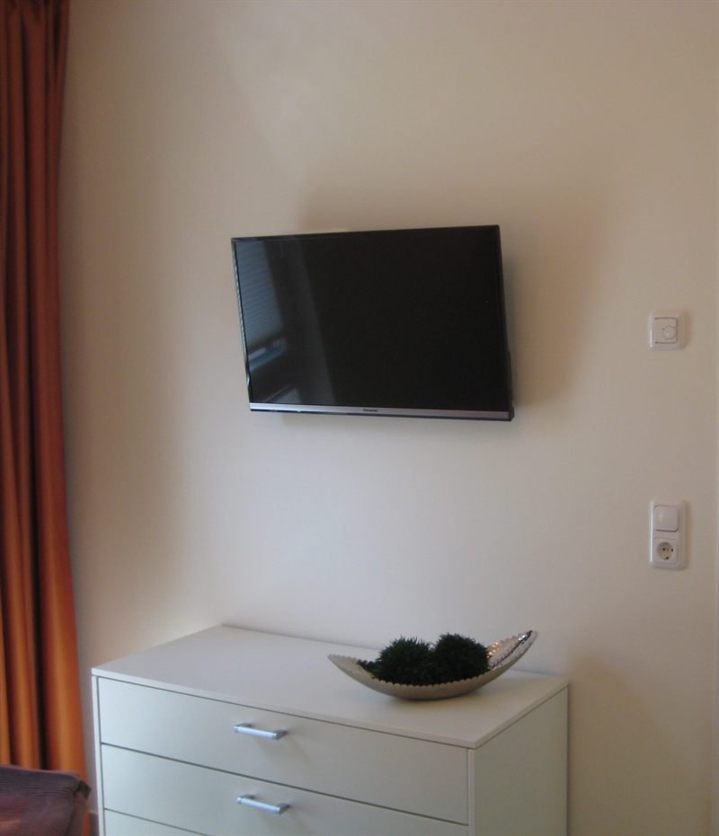 TV-Gerät an der Wand über einer Kommode im Schlafzimmer