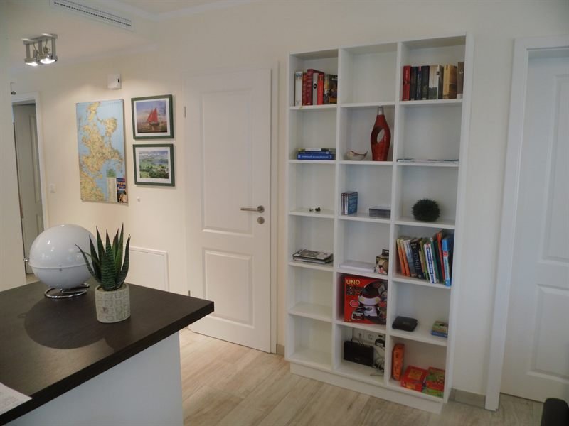 Wohnbereich mit hohem Bücherregal, Tresen und hellem Dielenboden